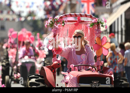 Il convoglio di trattori fare il suo modo attraverso Harleston in Norfolk durante la quindicesima signore in rosa su strada del trattore correre in aiuto del Cancer Research UK. Foto Stock