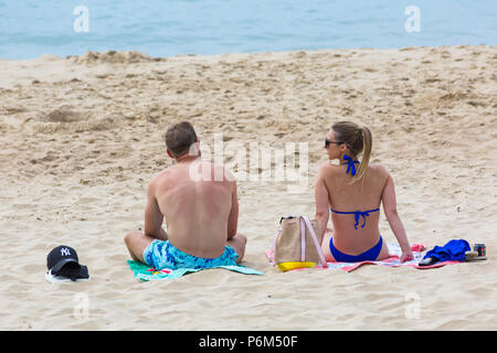 Bournemouth Dorset, Regno Unito. Il 1 luglio 2018. Regno Unito: meteo sole nebuloso, ma ancora caldo come migliaia di testa sunseekers per le spiagge di Bournemouth per godere di una giornata al mare. Matura a prendere il sole sulla spiaggia, torna in vista posteriore Credito: Carolyn Jenkins/Alamy Live News Foto Stock