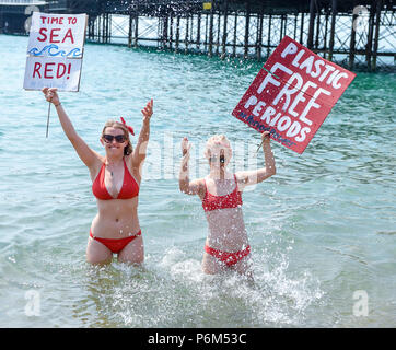 Brighton Regno Unito 1 Luglio 2018 - Gli attivisti raffreddare in mare sulla spiaggia di Brighton su un bel sole caldo giorno dopo aver preso parte in plastica periodo libero prodotti corteo di protesta lungo il lungomare per contrassegnare l'inizio della campagna per mostrare il vostro #periodpower questo luglio Natracare la UKs plastica leader periodo gratuito brand ha unito le forze con il Marine Conservation Society per rivelare la scioccante impatti ambientali del periodo dei rifiuti sul litorale UK Credit: Simon Dack/Alamy Live News Foto Stock