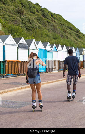 Bournemouth Dorset, Regno Unito. Il 1 luglio 2018. Regno Unito: meteo sole nebuloso, ma ancora caldo come migliaia di testa sunseekers per le spiagge di Bournemouth per godere di una giornata al mare. Maschio e femmina rollerskating lungo la promenade, torna in vista posteriore Credito: Carolyn Jenkins/Alamy Live News Foto Stock
