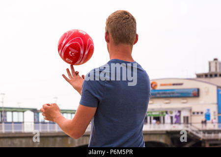 Bournemouth Dorset, Regno Unito. Il 1 luglio 2018. Regno Unito: meteo sole nebuloso, ma ancora caldo come migliaia di testa sunseekers per le spiagge di Bournemouth per godere di una giornata al mare. Maschio sfera di filatura sul dito, retro vista posteriore con il Molo di Bournemouth dietro. Credito: Carolyn Jenkins/Alamy Live News Foto Stock