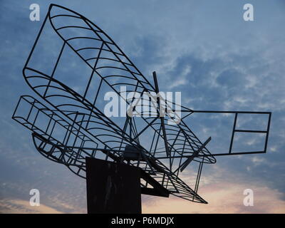 Eastchurch, UK. 1 Luglio, 2018. Regno Unito Meteo: il tramonto dietro la bi-piano scultura in Eastchurch, Kent. Eastchurch villaggio sull'Isle of Sheppey celebrato cento anni di storia dell'aviazione nel luglio del 2009, che la scultura è stata installata per commemorare i. Il primo volo controllato da un pilota britannico sul suolo britannico ha avuto luogo all'estremità orientale dell'isola di Sheppey, che è conosciuto come il luogo di nascita di aviazione britannica. Credito: James Bell/Alamy Live News Foto Stock