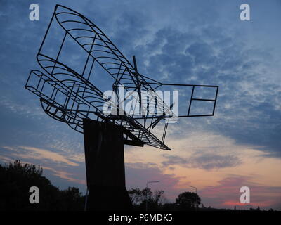 Eastchurch, UK. 1 Luglio, 2018. Regno Unito Meteo: il tramonto dietro la bi-piano scultura in Eastchurch, Kent. Eastchurch villaggio sull'Isle of Sheppey celebrato cento anni di storia dell'aviazione nel luglio del 2009, che la scultura è stata installata per commemorare i. Il primo volo controllato da un pilota britannico sul suolo britannico ha avuto luogo all'estremità orientale dell'isola di Sheppey, che è conosciuto come il luogo di nascita di aviazione britannica. Credito: James Bell/Alamy Live News Foto Stock