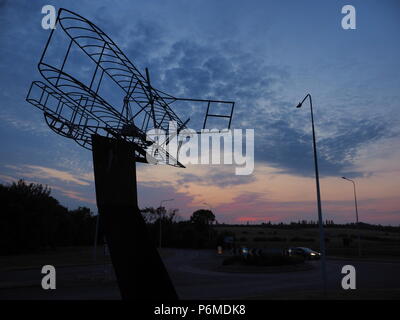 Eastchurch, UK. 1 Luglio, 2018. Regno Unito Meteo: il tramonto dietro la bi-piano scultura in Eastchurch, Kent. Eastchurch villaggio sull'Isle of Sheppey celebrato cento anni di storia dell'aviazione nel luglio del 2009, che la scultura è stata installata per commemorare i. Il primo volo controllato da un pilota britannico sul suolo britannico ha avuto luogo all'estremità orientale dell'isola di Sheppey, che è conosciuto come il luogo di nascita di aviazione britannica. Credito: James Bell/Alamy Live News Foto Stock