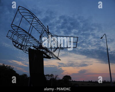 Eastchurch, UK. 1 Luglio, 2018. Regno Unito Meteo: il tramonto dietro la bi-piano scultura in Eastchurch, Kent. Eastchurch villaggio sull'Isle of Sheppey celebrato cento anni di storia dell'aviazione nel luglio del 2009, che la scultura è stata installata per commemorare i. Il primo volo controllato da un pilota britannico sul suolo britannico ha avuto luogo all'estremità orientale dell'isola di Sheppey, che è conosciuto come il luogo di nascita di aviazione britannica. Credito: James Bell/Alamy Live News Foto Stock