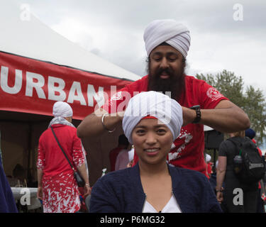 Calgary, Canada. 1 Luglio, 2018. La donna ottiene turbante legato al turbante, eh?, un evento ospitato dal Mondo Organizzazione Sikh al principe Island Park sul Canada il giorno. Le persone sono state invitate ad avere un colore rosso o bianco turbante avvolto attorno alla loro testa e conoscere la cultura Sikh. Rosanne Tackaberry/Alamy Live News Foto Stock