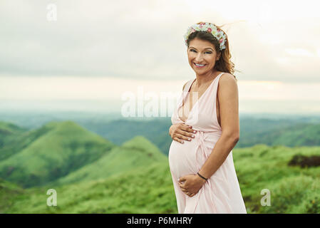 Asian donna incinta naturale su sfondo verde Foto Stock