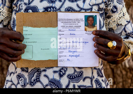 Membro di una donna cooperativa di microfinanza che mostra il suo libretto di risparmio nel nord del Togo. Foto Stock
