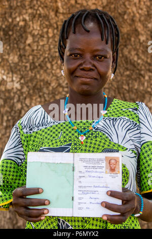 Membro di una donna cooperativa di microfinanza che mostra il suo libretto di risparmio nel nord del Togo. Foto Stock
