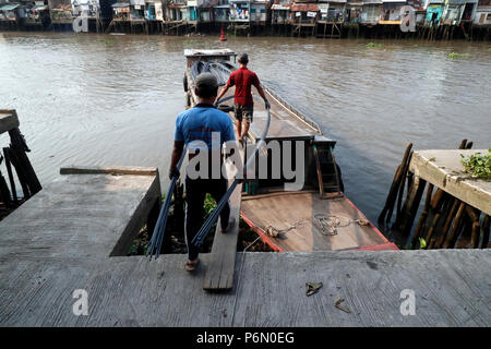 Mercato galleggiante lungo il fiume Mekong. Tondino in acciaio per cemento armato costruzione edilizia. Lavoratori edili. In Cai Be. Il Vietnam. Foto Stock