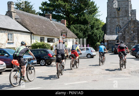 Drewsteignton, Devon, Inghilterra, Regno Unito. I ciclisti in sella attraverso questo pittoresco villaggio nel nord zona Dartmoor. Foto Stock