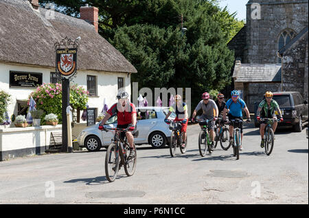 Drewsteignton, Devon, Inghilterra, Regno Unito. I ciclisti in sella attraverso questo pittoresco villaggio nel nord zona Dartmoor. Foto Stock