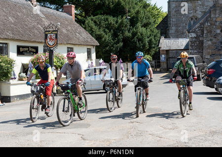 Drewsteignton, Devon, Inghilterra, Regno Unito. I ciclisti in sella attraverso questo pittoresco villaggio nel nord zona Dartmoor. Foto Stock