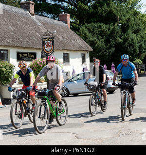 Drewsteignton, Devon, Inghilterra, Regno Unito. I ciclisti in sella attraverso questo pittoresco villaggio nel nord zona Dartmoor. Foto Stock