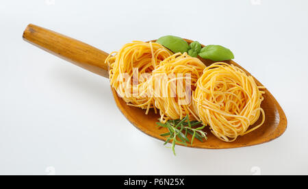 Fasci di spaghetti e le erbe in un cucchiaio di legno Foto Stock