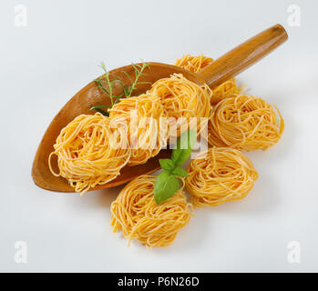 Fasci di spaghetti e le erbe in un cucchiaio di legno Foto Stock