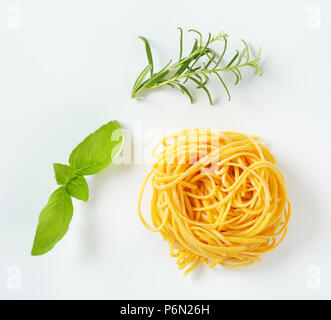 Bundle di spaghetti ed erbe fresche su sfondo bianco Foto Stock