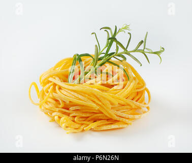Bundle di spaghetti con rosmarino su sfondo bianco Foto Stock