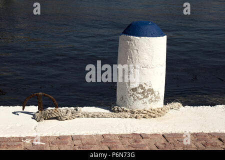 Tradizionale di pietra bollard, dipinta di bianco e blu, con piccoli vecchi ancora con la corda, Telendos, Kalymnos, Grecia Foto Stock