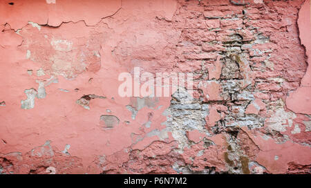 Telaio completo sullo sfondo di un weathered, danneggiato e muro intonacato dipinta in rosa. Il gesso è parzialmente distaccata rivelando vecchi mattoni. Foto Stock