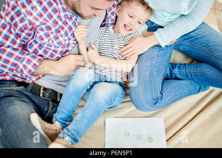 I genitori solletico carino piccolo ragazzo Foto Stock