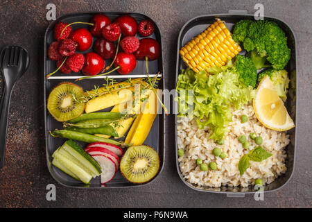 Pasto sano prep contenitori con riso marrone, broccoli, ortaggi e frutta e bacche overhead shot con copia spazio, backrground scuro, vista dall'alto Foto Stock