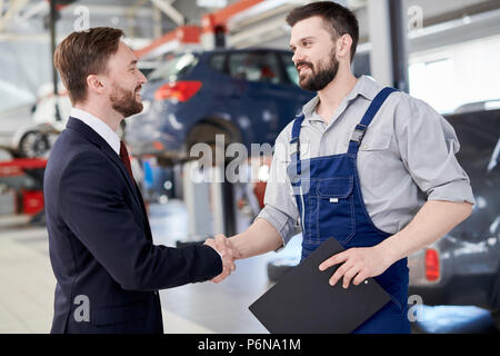 Mechanic stringono le mani con il proprietario Foto Stock