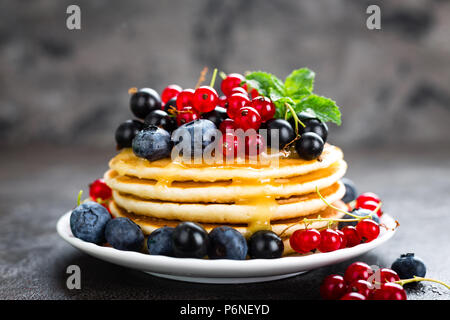 Frittelle con frutti di bosco freschi. Frittelle di lampone, mirtillo, ribes rossi, ribes e miele Foto Stock