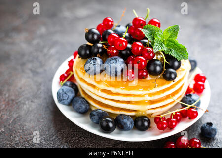 Frittelle con frutti di bosco freschi. Frittelle di lampone, mirtillo, ribes rossi, ribes e miele Foto Stock