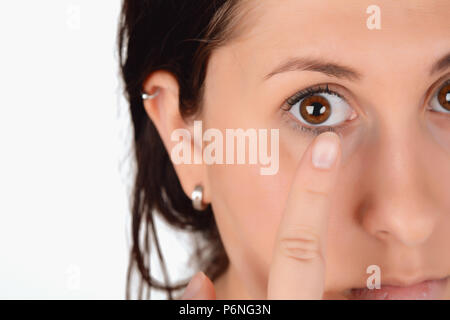 Primo piano della faccia femmina con applicazione di lente a contatto sui suoi occhi marroni. Oftalmologia medicina concetto. Foto Stock