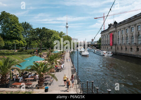 Berlino, Germania - Giugno 2018: persone presso il beach bar accanto al fiume Spree con battelli turistici e la torre della TV in background Foto Stock