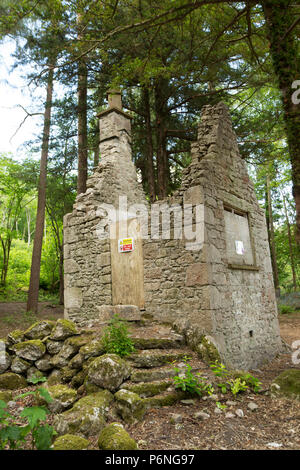 I resti di un cottage in pietra con terreno cancellata attorno ad esso nel bosco in prossimità di Hawes lago d acqua in Silverdale con cartelli di avvertimento di non entrare. Hawes Wa Foto Stock