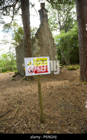 I resti di un cottage in pietra con terreno cancellata attorno ad esso nel bosco in prossimità di Hawes lago d acqua in Silverdale con cartelli di avvertimento di non entrare. Hawes Wa Foto Stock