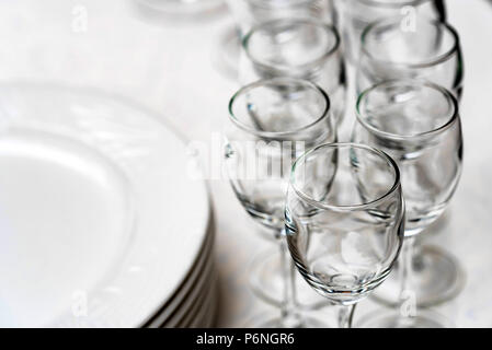 Pila di piastre bianche vuote e bicchieri di vino Foto Stock