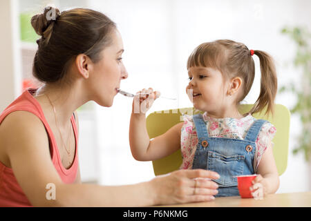 Giocoso bambina cucchiaio alimentazione di sua madre Foto Stock