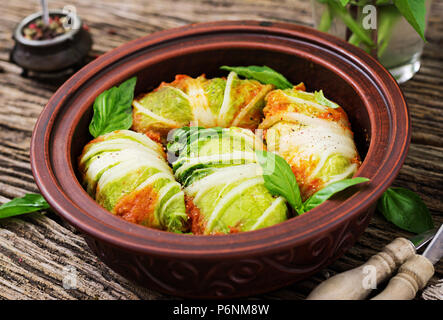 Involtini di cavolo ripiene di riso con filetto di pollo in salsa di pomodoro su un sfondo di legno. Il cibo gustoso. Foto Stock