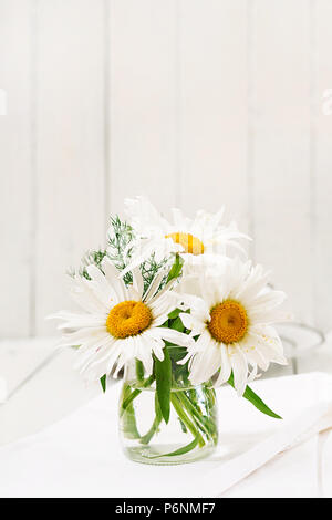 Bouquet di margherite in vaso su una tavola di legno tavolo bianco Foto Stock
