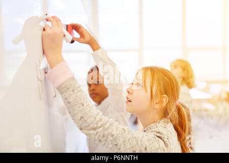 I bambini di risolvere compito insieme su una lavagna nella scuola elementare Foto Stock