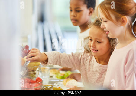 Bambini pick up food presso la caffetteria a buffet in asilo nido o alla scuola elementare Foto Stock