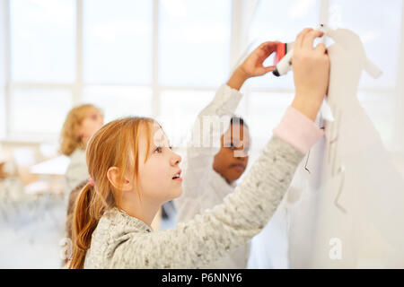 I bambini sono considerati insieme sulla lavagna in lezioni di matematica della scuola elementare Foto Stock