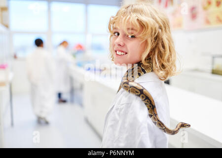 Ragazzo colpi un serpente sulla sua spalla nella scuola elementare laboratorio di biologia Foto Stock