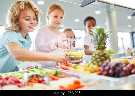 Allievi felici prendere frutta fresca dalla caffetteria è a buffet Foto Stock