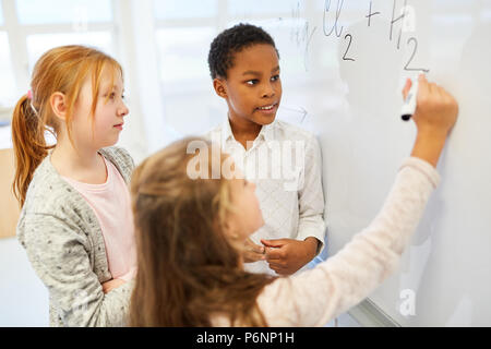 Un gruppo di bambini nella lezione di matematica calcola un compito sulla lavagna Foto Stock