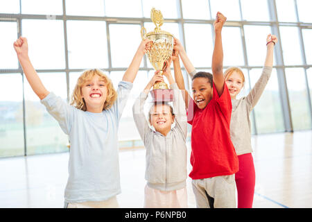 Un gruppo di bambini come team di successo con tazza cheers dopo un concorso Foto Stock