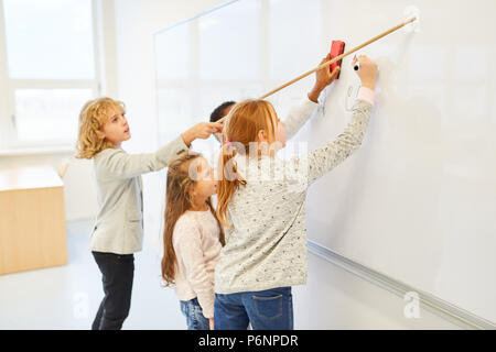 I bambini come gli studenti di risolvere un compito di matematica sulla lavagna in lavoro di squadra Foto Stock