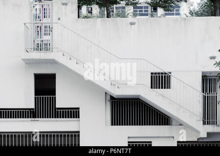 Architettonica di sfondo - Griglia windows di diverse forme e dimensioni in calcestruzzo bianco parete, una scala esterna sulla costruzione. Foto Stock