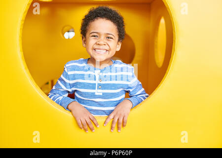 Felice ragazzo giocando in area di gioco Foto Stock