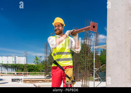 Colletto blu lavoratore portando una pesante barra metallica durante il lavoro Foto Stock