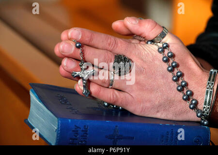 Uomo con anello di cranio pregando il rosario. Close-up. La Francia. Foto Stock