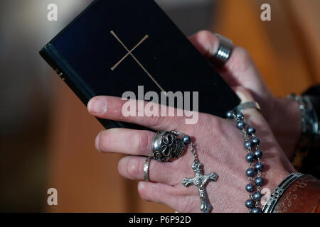 Uomo con anello di cranio pregando il rosario e la lettura della Bibbia. Close-up. La Francia. Foto Stock